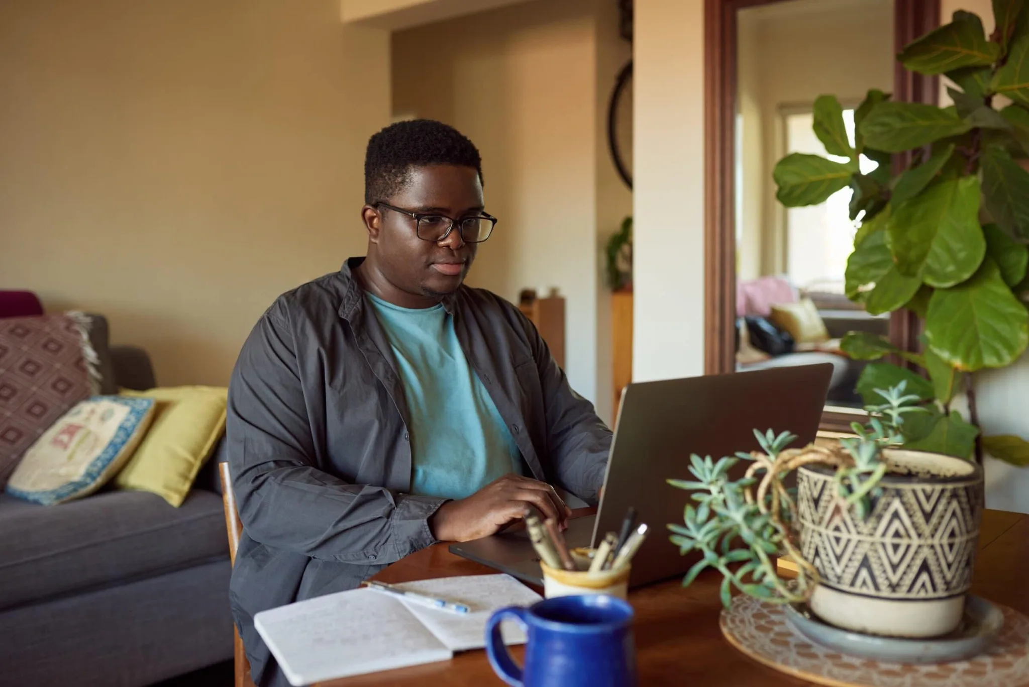 Young,African,Man,Sitting,At,A,Table,At,Home,Going